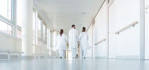 Drei Ärzte, die einen Flur im Krankenhaus hinuntergehen